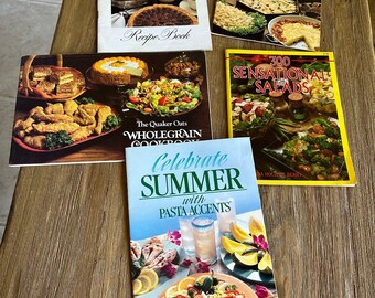 May include: A collection of five cookbooks with colorful covers featuring various food items. The cookbooks are titled "Favorite Potato Recipes from Betty Crocker", "Recipe Book", "The Quaker Oats Wholegrain Cookbook", "300 Sensational Salads", and "Celebrate Summer with Pasta Accents".