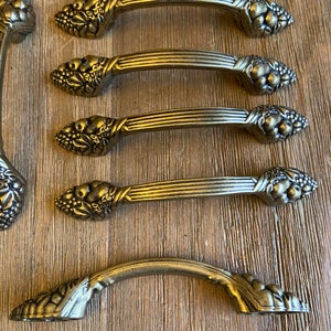 May include: Set of seven antique brass cabinet knobs with a grape and leaf design. The knobs are in excellent condition and have a beautiful patina.