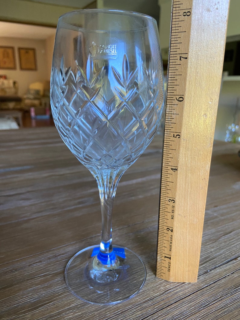May include: A clear glass wine glass with a cut crystal design. The glass is 17.8 cm tall and has a Schott Zwiesel logo on the side.
