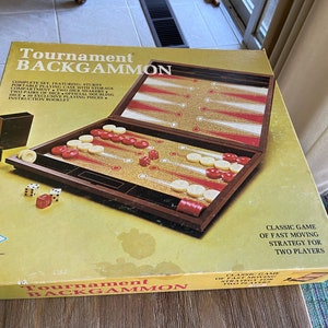 May include: A vintage wooden backgammon game set in a brown box with gold lettering. The box says "Tournament Backgammon" and "Classic Game of Fast Moving Strategy for Two Players".