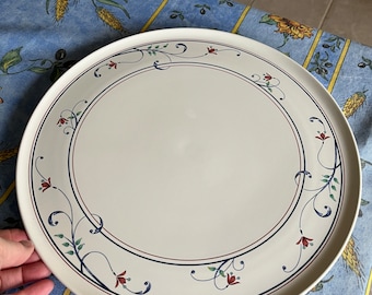 May include: A white ceramic serving platter with a blue and red floral design. The platter has a raised rim and a smooth surface.