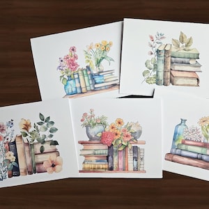 May include: Watercolor illustrations of books and flowers on white cards. Each card features a unique arrangement of colorful books, vases, and vibrant flowers. The artwork has a soft, artistic style, perfect for home decor.