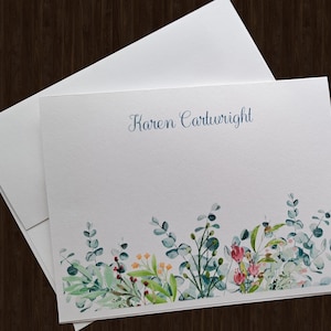 May include: White stationery with a blue floral border and the name "Karen Cartwright" printed in blue ink.