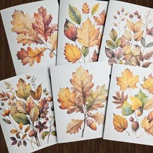 May include: A collection of six watercolor art prints featuring detailed illustrations of autumn leaves in shades of yellow, orange, and brown. The prints showcase various leaf types and arrangements, perfect for fall decor.