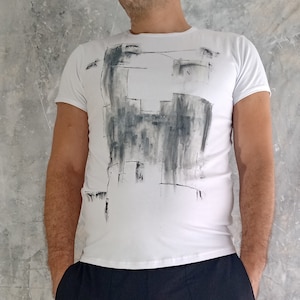 May include: White t-shirt with a black and gray abstract design.