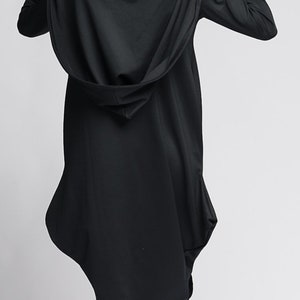 Op de afbeelding: Een zwarte tuniek met capuchon en een lang, vloeiend ontwerp. De tuniek is gemaakt van een zachte, comfortabele stof en heeft een losse pasvorm.