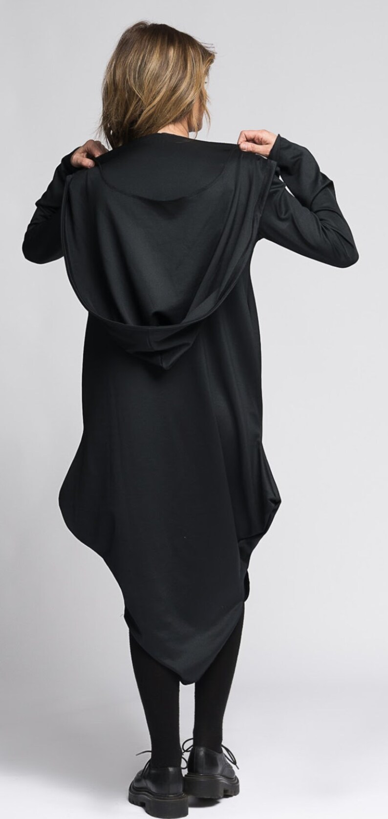 Op de afbeelding: Een zwarte tuniek met capuchon en een lang, vloeiend ontwerp. De tuniek is gemaakt van een zachte, comfortabele stof en heeft een losse pasvorm.