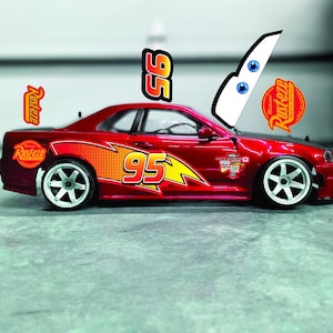 May include: A red toy car with the number "95" and lightning bolt graphics on the side. The car has white wheels and the "Rust-eze" logo. Additional decals include the number "95" and the word "LIGHTNG".