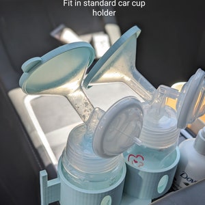 May include: A light blue plastic car cup holder with two clear bottles and blue and white pump parts. The text "Fit in standard car cup holder" is visible above the holder.