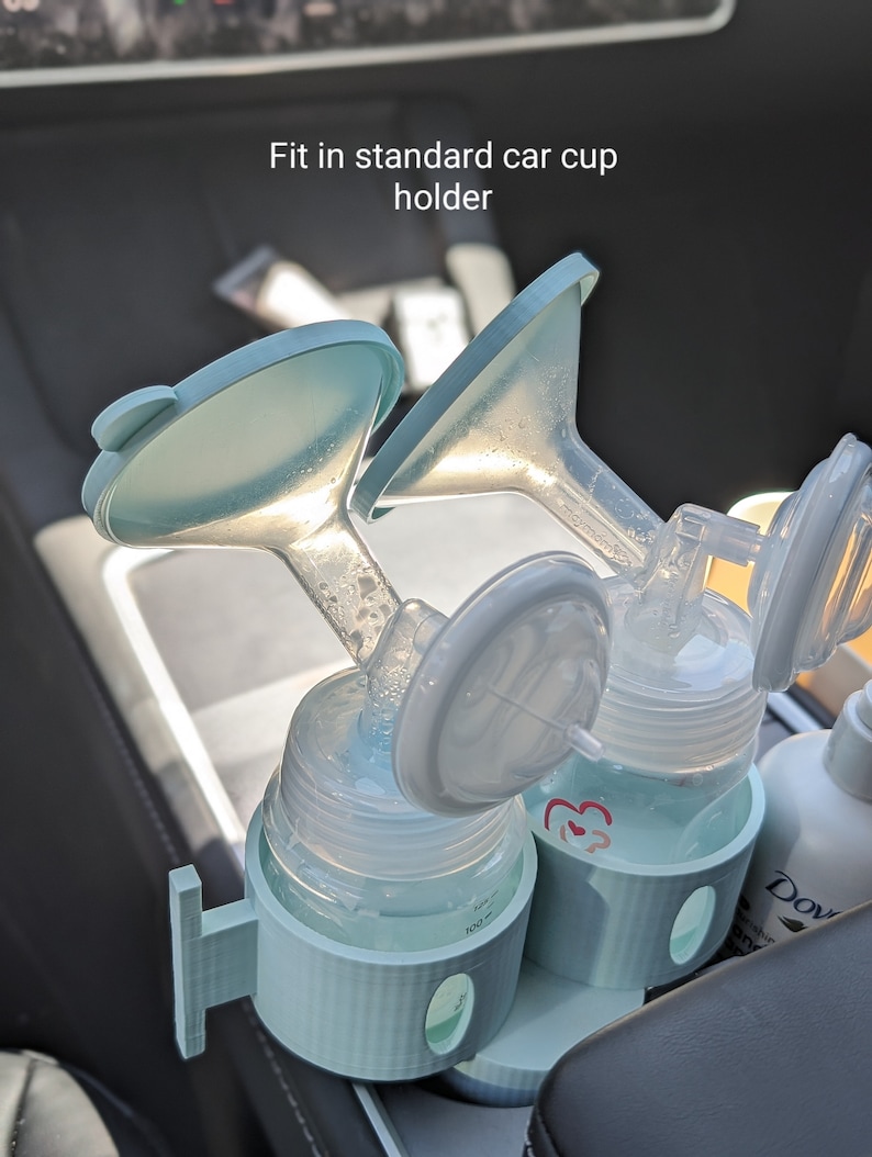 May include: A light blue plastic car cup holder with two clear bottles and blue and white pump parts. The text "Fit in standard car cup holder" is visible above the holder.