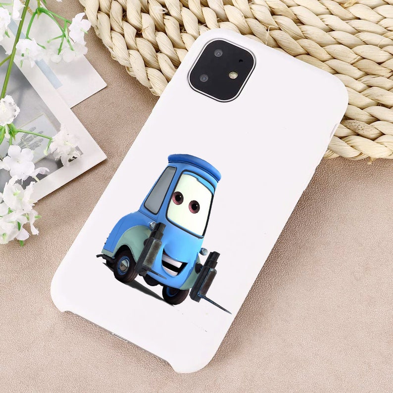 Puede incluir: Carcasa de tel&eacute;fono blanca con una imagen de dibujos animados de una carretilla elevadora azul con una cara sonriente. La carcasa del tel&eacute;fono tiene un recorte para la c&aacute;mara en la esquina superior izquierda.