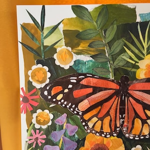 May include: A paper collage artwork featuring a large monarch butterfly with orange, black, and white wings. The butterfly is surrounded by various paper-cut flowers in shades of yellow, pink, and purple, set against a background of green foliage.
