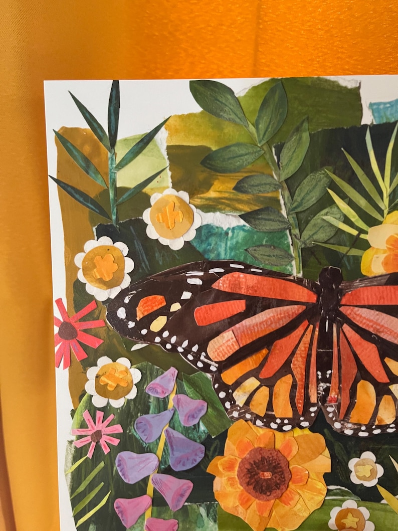 May include: A paper collage artwork featuring a large monarch butterfly with orange, black, and white wings. The butterfly is surrounded by various paper-cut flowers in shades of yellow, pink, and purple, set against a background of green foliage.