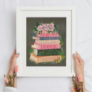 K&ouml;nnte beinhalten: Ein Stapel alter B&uuml;cher mit floralen Illustrationen und Titeln wie "Naturgeschichte", "Wildblumen", "Feen", "Blumen G&auml;rten" und "Eigenanbau". Eine Teetasse mit rosa Blumen steht oben auf dem Stapel.