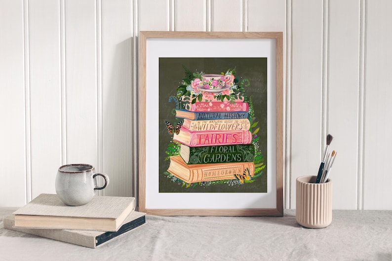 K&ouml;nnte beinhalten: Ein gerahmter Druck einer Stapel B&uuml;cher mit Titeln wie "Naturgeschichte", "Wildblumen", "Feen" und "Blumen G&auml;rten". Eine Teetasse und ein Untertasse mit Blumen liegen auf den B&uuml;chern.