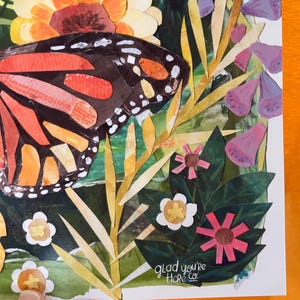 May include: A paper collage artwork featuring a large monarch butterfly with orange and black wings, surrounded by yellow, purple, and white flowers and green foliage. The text "glad you're Here co." is printed in white near the bottom right corner.