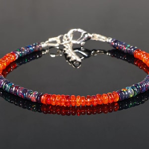May include: A silver bracelet with alternating orange and blue opal beads. The bracelet has a silver clasp.