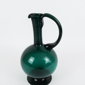 May include: A dark green glass pitcher with a round body and a curved handle.