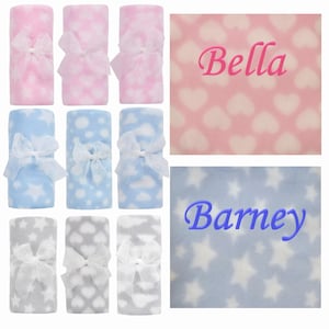 May include: Six personalised baby blankets in pink, blue and grey. The blankets feature a heart, cloud or star pattern. The names "Bella" and "Barney" are embroidered on the blankets.