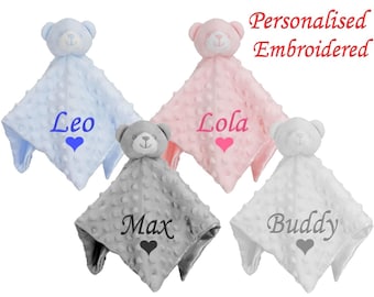 Pode incluir: Quatro mantas de bebé personalizadas bordadas com um urso de peluche anexado. As mantas são azuis, cor-de-rosa, cinzentas e brancas. Os nomes Leo, Lola, Max e Buddy estão bordados nas mantas.