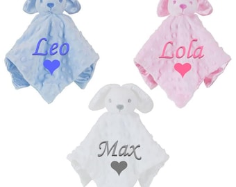 Pode incluir: Três mantas de bebé personalizadas com cabeças de coelho. As mantas são azuis, cor-de-rosa e brancas com os nomes "Leo", "Lola" e "Max" bordados.