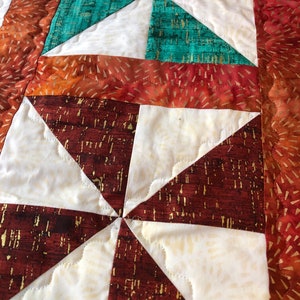 Table runner with n oranges, greens with orange cold flecked batik borders and binding.  Approximately 54”x15.5”