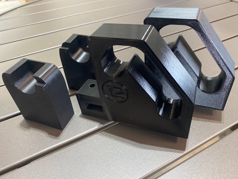 May include: Three black 3D printed corner brackets with a circular cutout. The brackets have a logo that says "T2" on them.