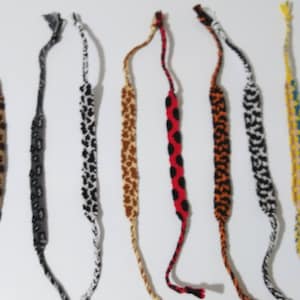 May include: Ten colorful friendship bracelets with various patterns, including animal print, polka dots, and geometric designs.