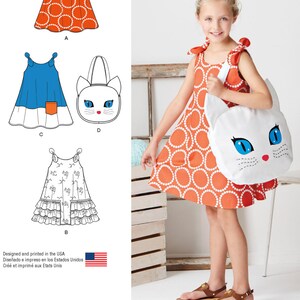 May include: Sewing pattern for a girl's dress and matching cat-shaped bag. The dress has a sleeveless design with a tie at the shoulders. The bag has a white fabric with a black cat face and blue eyes. The pattern is designed and printed in the USA.