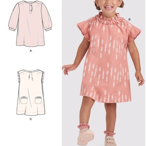 May include: A sewing pattern for a girl's dress with three different styles. The pattern includes a long-sleeved dress with a button closure, a sleeveless dress with a ruffle collar, and a sleeveless dress with pockets. The pattern is for sizes 12 months to 6 years.