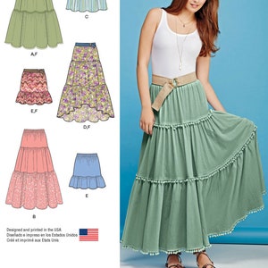 May include: A sewing pattern for a tiered skirt with different variations. The pattern includes a green skirt with a white belt, a pink skirt with a white belt, a floral skirt with a brown belt, a striped skirt, and a blue skirt. The pattern is designed and printed in the USA.