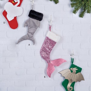 Op de afbeelding: Vier verschillende kerstsokpatronen met verschillende dierendesigns. Een grijze haaiensok, een roze zeemeerminsok, een groene drakensok en een rode zwanensok.