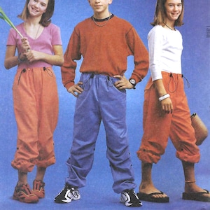 May include: Sewing pattern for trousers with a drawstring waist and cuffed legs. The pattern is shown on three models wearing different coloured trousers: orange, blue, and red.