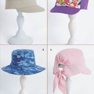 May include: Four different sewing patterns for hats. The patterns include a camouflage bucket hat, a pink hat with a bow, a beige military style hat, and a purple and floral baseball cap.