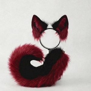 以下が含まれることがあります： 赤と黒のフェイクファーの耳が付いたヘアバンドと、お揃いの尻尾が特徴のコスプレアクセサリーセット。 尻尾は黒い中心と赤い縁を持つ湾曲した形状です。 耳は黒いヘアバンドに取り付けられています。