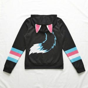 Könnte beinhalten: Schwarzer Kapuzenpullover mit Fuchsschwanz-Design. Die Kapuze hat rosa Ohrenakzente, und die Ärmel haben blaue, weiße und rosa Streifen. Der Fuchsschwanz ist weiß und blau.