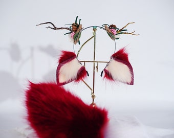 May include: A red fluffy tail with a white and pink faux fur headband with a floral design. The headband is on a gold stand.