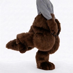 May include: Brown furry costume feet and legs with black claws. The costume has a grey top. The faux fur is a rich, dark brown colour. The costume is designed to resemble a bear or other animal.