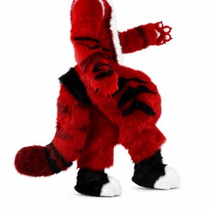 Può includere: Un costume da animale a corpo intero realizzato in pelliccia sintetica rosso vivace con distintive strisce nere simili a quelle di una tigre. L'abito include una lunga coda a righe, pelliccia nera sulla parte inferiore delle gambe e piedi bianchi.