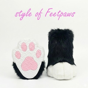 a pair of black and white cat paw slippers with pink paw prints, accompanied by the text "style of Feetpaws" in pink.