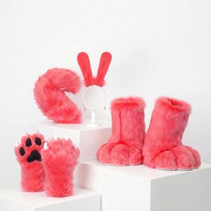 May include: A set of bright pink faux fur accessories including a pair of paw-shaped gloves with black pads and white claws, a pair of furry boot covers, a long curved tail, and a headband featuring two tall, upright pink rabbit-style ears.