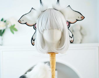 May include: White faux fur headband with black and pink butterfly wings and a matching white faux fur tail. The headband is on a white wig head.