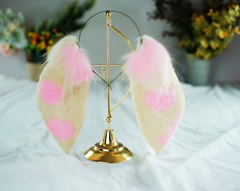 May include: A pair of white and pink furry bunny ears with pink spots on a gold stand.