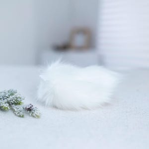 May include: A white fluffy pom pom, perfect for adding a touch of whimsy to crafts and projects.