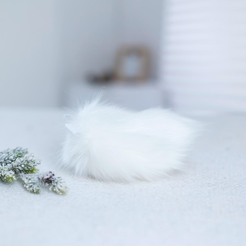 May include: A white fluffy pom pom, perfect for adding a touch of whimsy to crafts and projects.