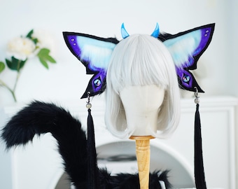 May include: A black faux fur tail with a pair of blue and purple butterfly wings with black tassels. The wings are attached to a white wig head.