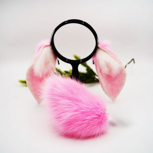 May include: Pink fluffy bunny tail and ears with white tips. The ears are attached to a black headband.