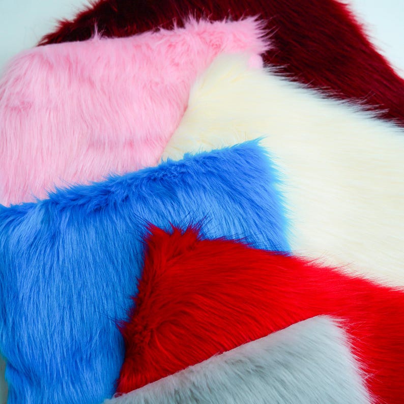 May include: A close-up of several pieces of faux fur in various colors. The colors include pink, blue, red, white, gray, and burgundy. The fur has a long, shaggy pile, and the pieces are arranged in a layered, overlapping pattern.