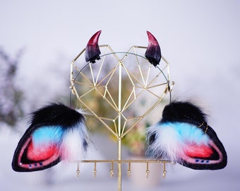 May include: Cosplay accessories set with a black headband, two red and black horns, and two fluffy ear-shaped pieces. The ear pieces have black, white, blue, and red fur, with a gold ring detail. The horns are approximately 5 cm tall.