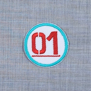 Puede incluir: Un c&iacute;rculo blanco con el n&uacute;mero rojo "01" en su interior, rodeado por un borde turquesa.